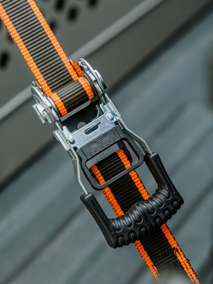 Durable ratchet strap with orange accents, ideal for secure cargo fastening.