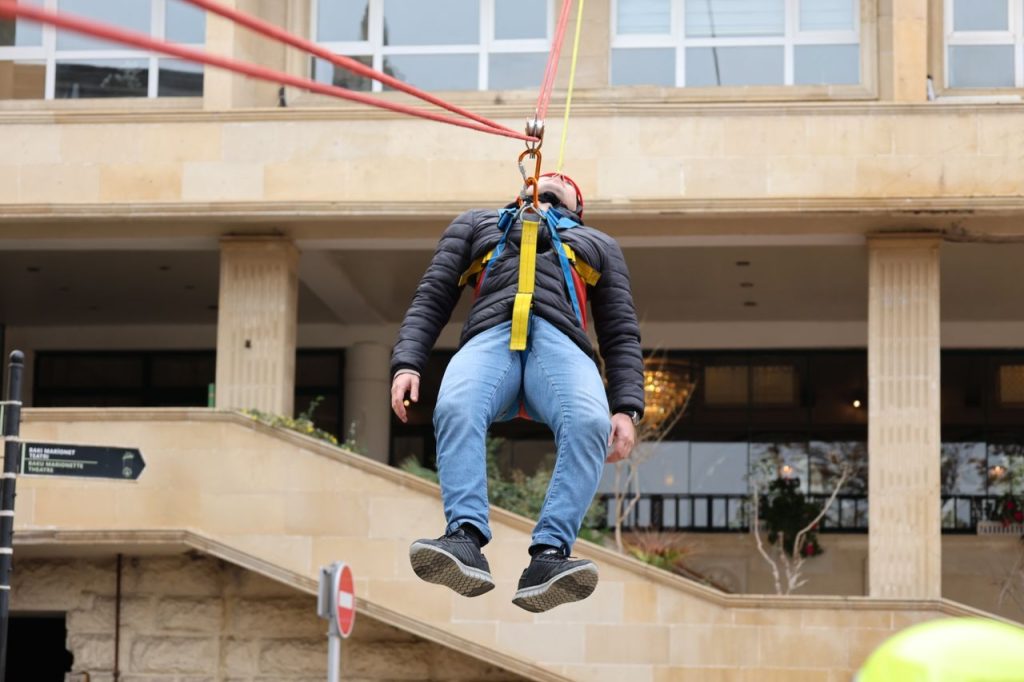 Man suspended in mid-air during an urban bungee jump activity outdoors.