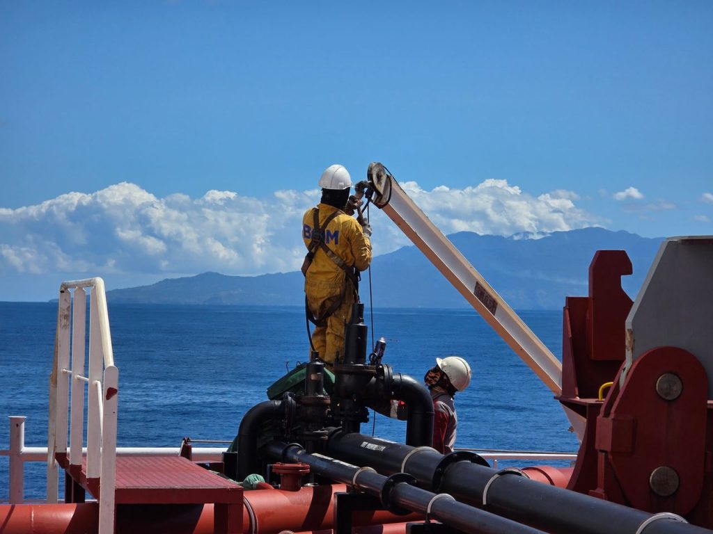 Workers on an offshore oil platform in Mozambique, performing maintenance work under clear skies.