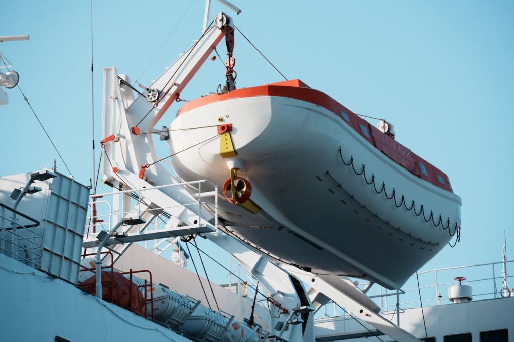 A lifeboat secured on the deck of a passenger ship, showcasing marine safety equipment under clear skies.