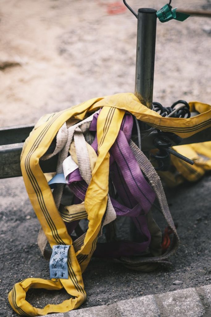 A bundle of colorful sewn slings and ropes attached to metal railings outdoors.